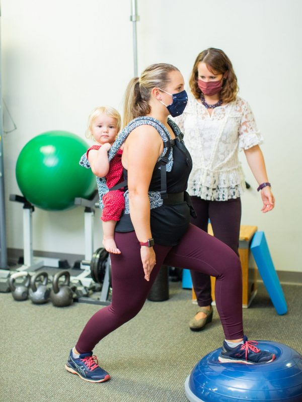 woman carries child at physical therapy